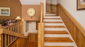 A wooden staircase with a wooden railing and a clock on the wall. - Private hot tub, multiple private decks, near Town Center - Spanish Peaks Perfection (Big Sky)