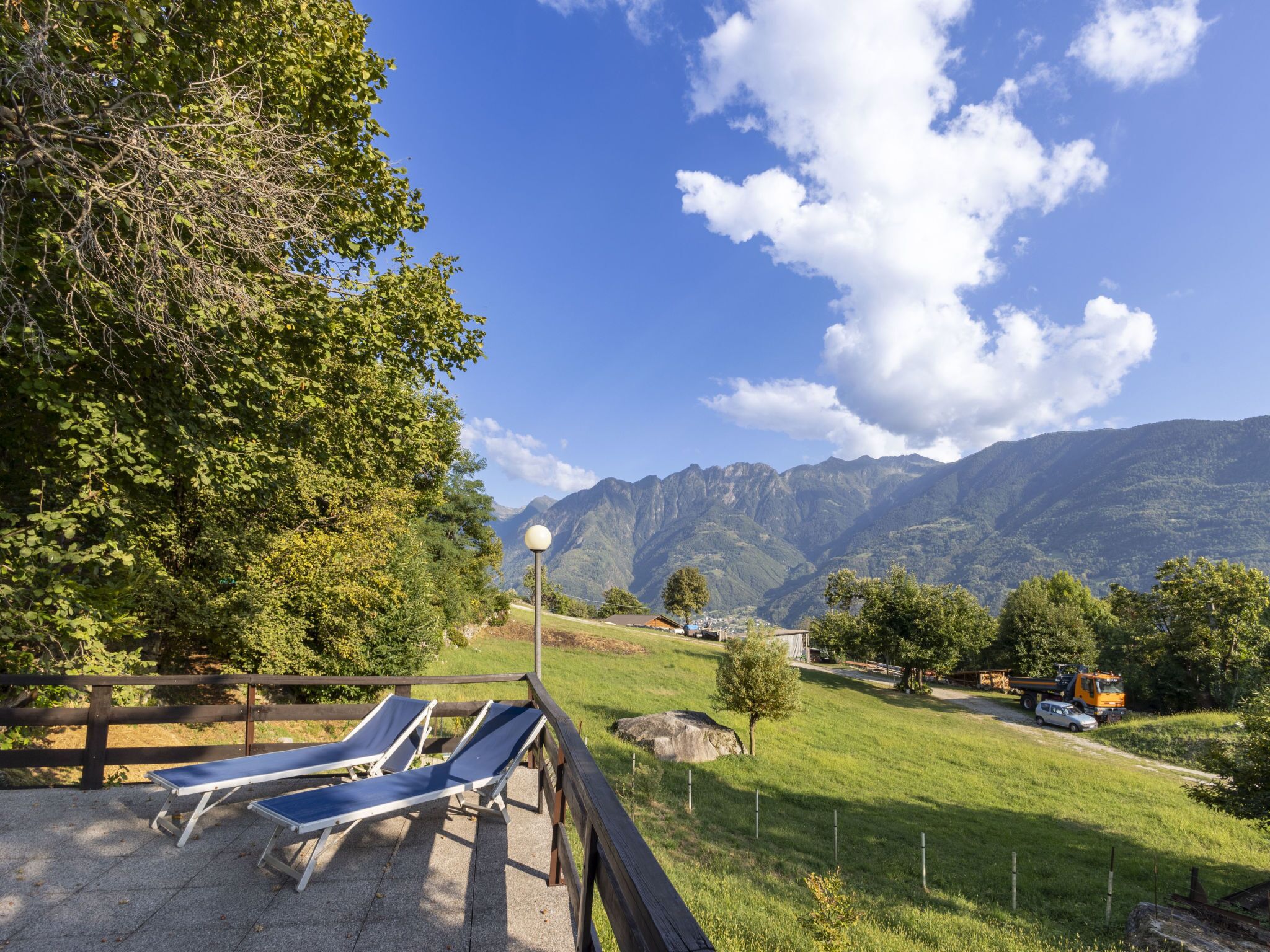 Eine Terrasse mit Liegestühlen mit Blick auf eine gebirgige Landschaft.
