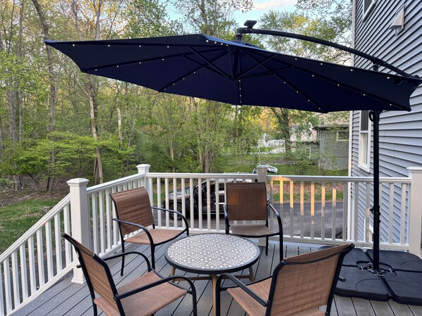 A deck with a round table and four chairs, surrounded by a white railing. - Modern/Luxury Condo Norwood (Norwood)