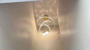 Een moderne trap met een unieke ronde lamp en een houten leuning.