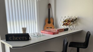 A bar area with a guitar, Scrabble boxes, and a 'cheers' sign.