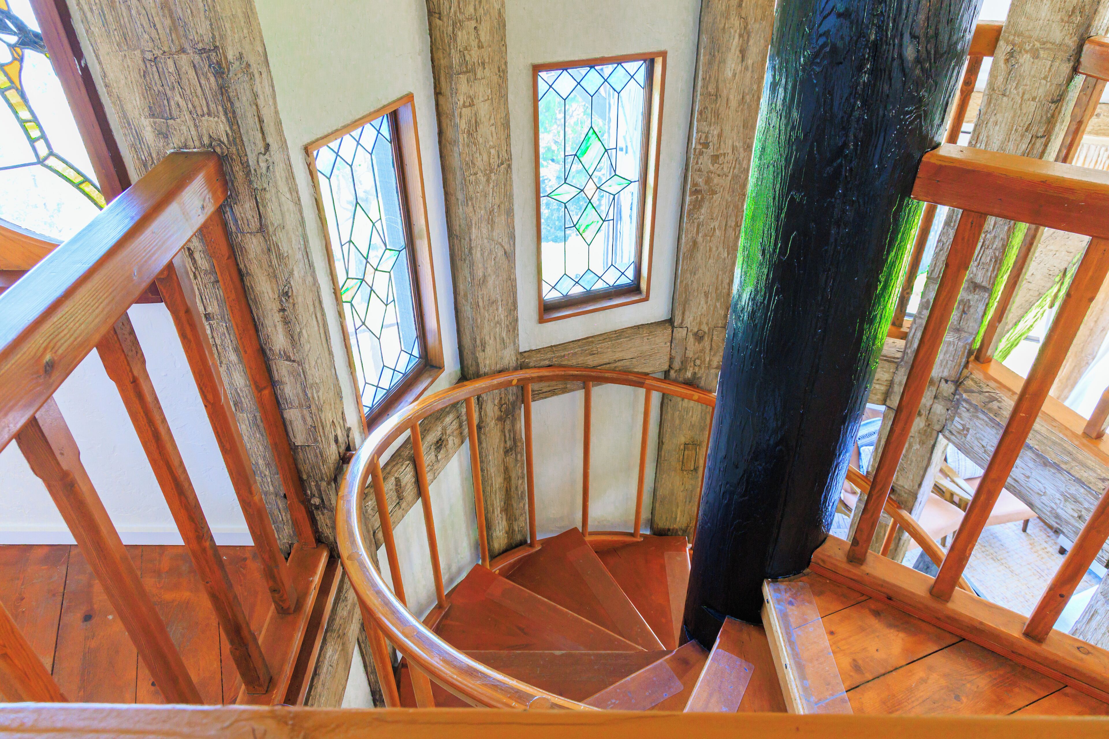 Eine Wendeltreppe aus Holz mit Holzwangen und einem farbigen Glasfenster.