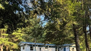 A mobile home with a blue roof and white siding, surrounded by trees and grass. - Private & Cozy! Close to the Clarion River & State Parks!- Camp Harv est.1994 (Clarington)