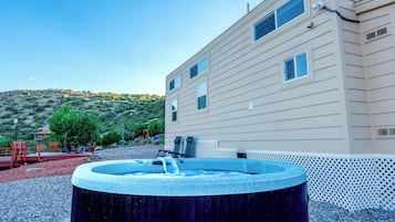 A building with a swimming pool, outdoor seating, and a view of a hilly landscape.