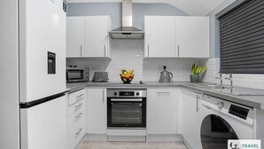 A modern kitchen with white cabinetry, a built-in oven, a microwave, and a coffee maker.