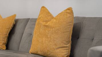 A grey sofa with two mustard-colored pillows.