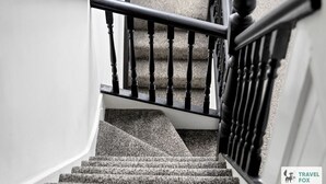 Una scala con ringhiera nera e corrimano bianco.
