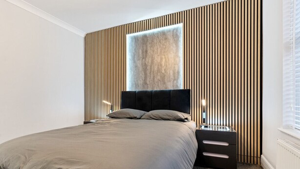 Camera da letto moderna con un letto grande, una testiera, un comodino e una finestra con persiane.