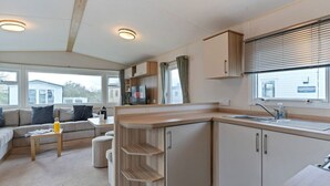 Un espacio habitable compacto con kitchenette, un sofá, una mesa de centro y una ventana con persianas.