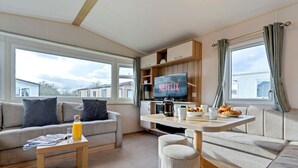 Una sala de estar moderna con un sofá, una mesa de centro, un televisor y una zona de cocina.