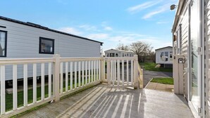 Una casa móvil con terraza de madera y valla blanca.