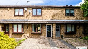 A two-story brick building with multiple windows, a front door, and a small garden area with gravel and plants. - Lily's Stay Central  Parking (Nottingham)