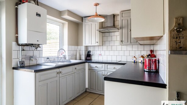A modern kitchen with white cabinets, a black countertop, a built-in oven, and a red coffee machine. - Lily's Stay Central  Parking (Nottingham)