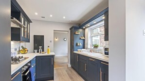 A modern kitchen with dark cabinetry, a central island, and a window providing natural light.