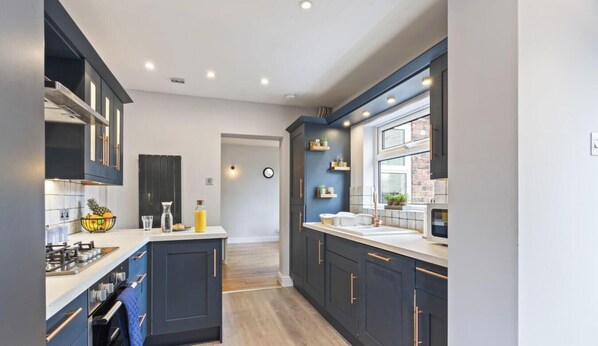 A modern kitchen with dark cabinetry, a central island, and a window providing natural light.
