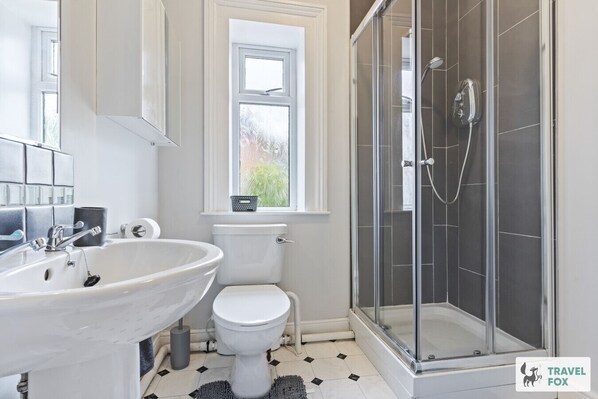 A bathroom with a white sink, toilet, and glass-enclosed shower.