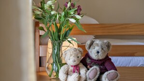 Een houten nachtkastje met een glazen vaas met bloemen en twee teddyberen.