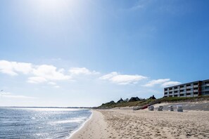 A beach with a building, clear sky, and calm sea. - Strandliebe - Modern app. with balcony, sea view, parking space, WLAN. (List auf Sylt)