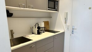 Een kleine keuken met een magnetron, koffiezetapparaat en een spoelbak.