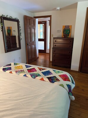 A bedroom with a bed, a dresser, a mirror, and a door leading to another room. - Rural suite with spectacular, sunrise and agricultural views. Pet Friendly! (Victoria)