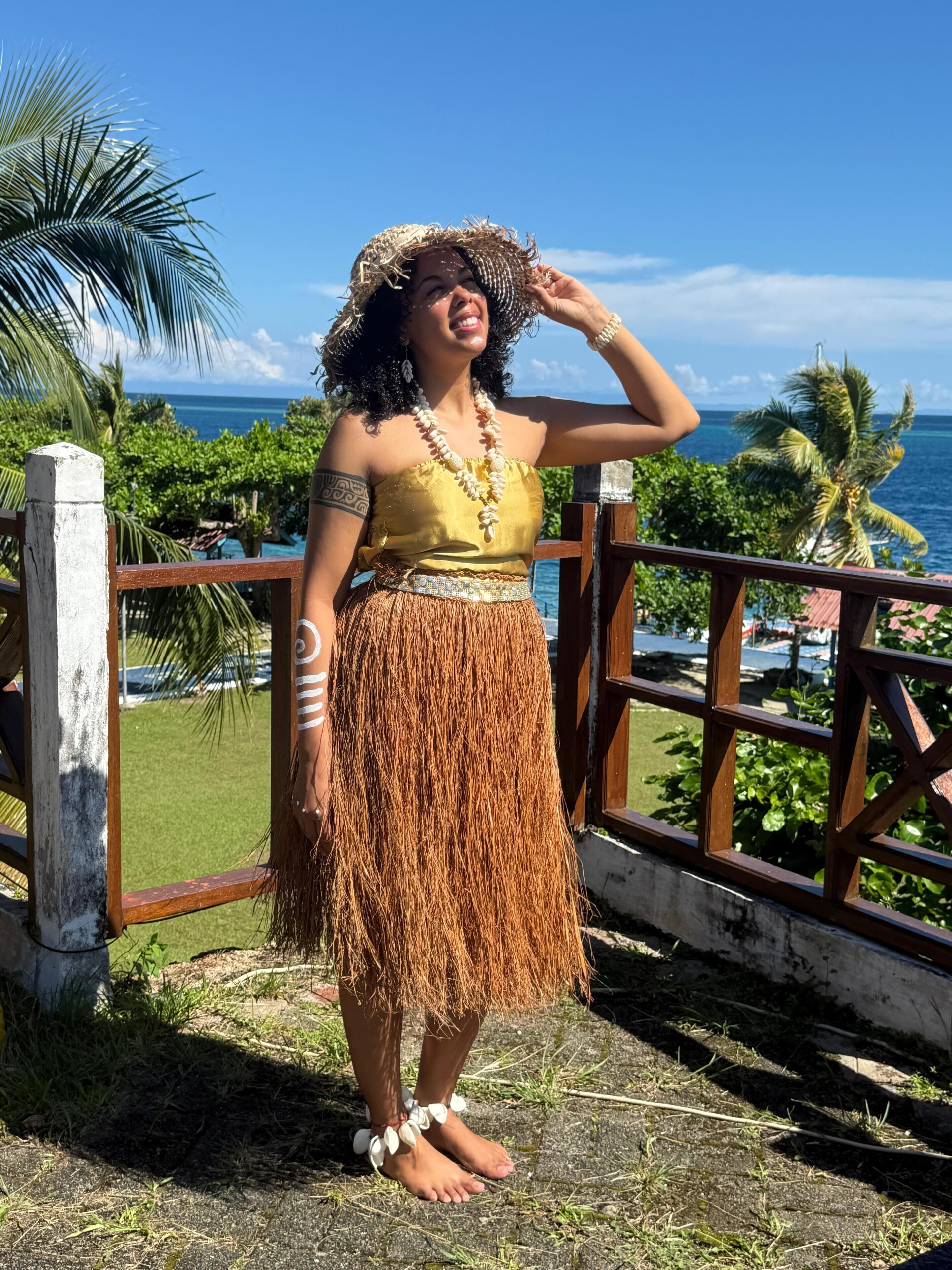 Una persona en un balcón contemplando el océano y palmeras.