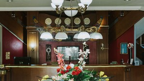 A reception area with a glass-top desk, a chandelier, and a clock on the wall. - Nirmala Beach Hotel and Resort Biak (Biak)
