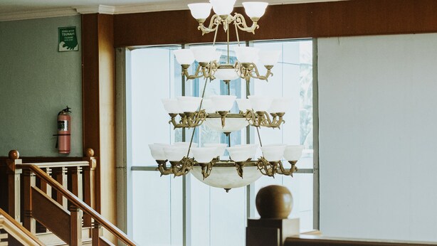 A staircase with wooden railings and a chandelier with multiple light fixtures. - Nirmala Beach Hotel and Resort Biak (Biak)