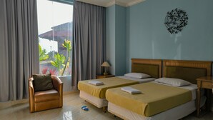 A hotel room with two beds, a chair, a lamp, and a view of the outdoors. - Nirmala Beach Hotel and Resort Biak (Biak)
