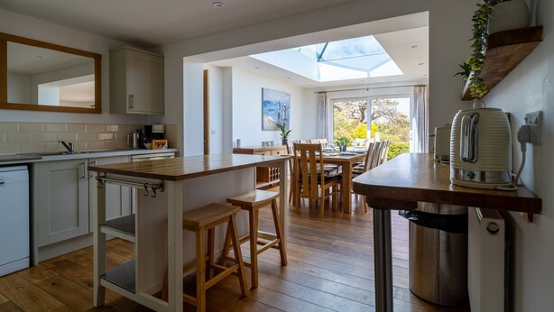A modern kitchen with wooden countertops, a dining area with a table and chairs, and a skylight.