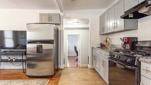 Uma cozinha moderna com eletrodomésticos de aço inoxidável, forno embutido e painel de backsplash em padrão herringbone.