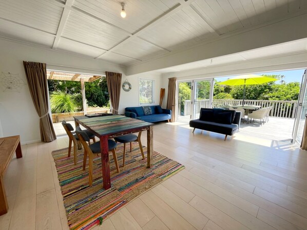A spacious living area with a wooden table, blue sofa, and a view of the outdoors through large sliding doors.