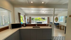 Eine moderne Küche mit Kochinsel, ein Essbereich mit Aussicht und ein Wohnraum mit Kamin.