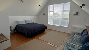 Ein Schlafzimmer mit einem Bett, einem Fenster mit Jalousien, einem Heizkörper und einem kleinen Nachttisch.