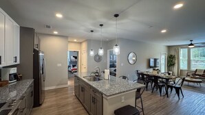 A modern kitchen with granite countertops, stainless steel appliances, and pendant lighting.