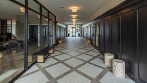 A modern hallway with glass partitions, wooden benches, and a patterned floor.