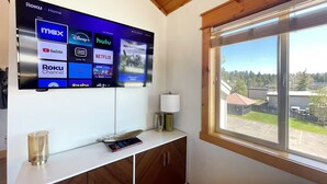 A modern living room with a large flat-screen TV displaying various streaming services.