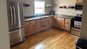 Una cocina con armarios de madera, electrodomésticos de acero inoxidable, encimera de granito y una ventana que proporciona luz natural.