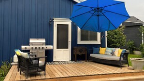 Une terrasse avec un barbecue, un canapé et un parasol.