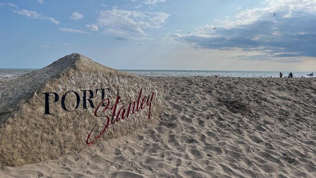 Une plage de sable avec une grande dune sur laquelle est inscrit le mot « PORT Stanley ».