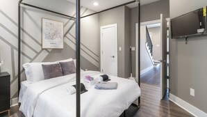 A modern hotel room with a bed, a map of Tokyo on the wall, a TV, and a staircase leading to another area.