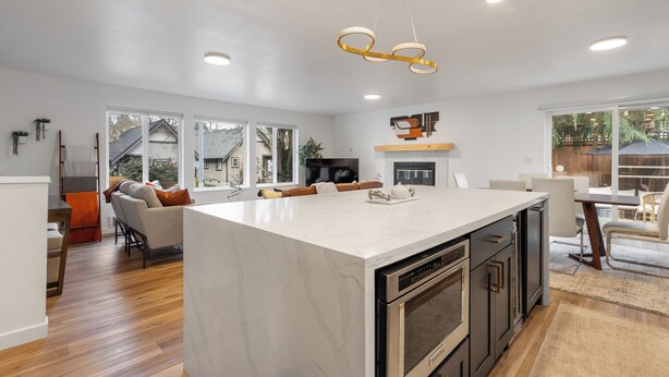 A spacious kitchen with a large island, modern appliances, and a dining area with a view. - Urban Oasis with Cedar Hot Tub (Seattle)