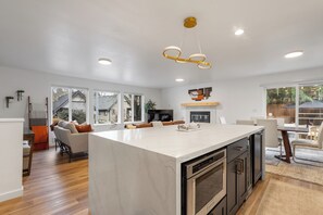 A spacious kitchen with a large island, modern appliances, and a dining area with a view. - Urban Oasis with Cedar Hot Tub (Seattle)