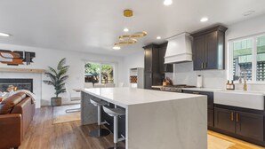 A modern kitchen with a large island, dark cabinetry, and a central island bar with stools. - Urban Oasis with Cedar Hot Tub (Seattle)