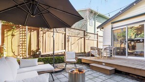 An outdoor patio with a fire pit, outdoor furniture, and a covered seating area. - Urban Oasis with Cedar Hot Tub (Seattle)
