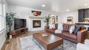 A modern living room with a fireplace, leather sofa, wooden coffee table, and a TV. - Urban Oasis with Cedar Hot Tub (Seattle)