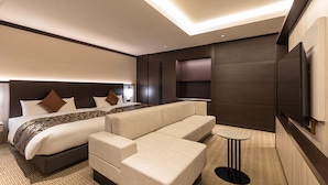 A modern hotel room with a large bed, a sofa, a TV, and a small table. - HOTEL R9 Premium Ichikawaekimae (Ichikawa)