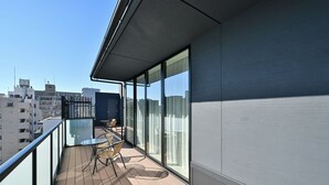 A balcony with a glass partition, a table, and chairs. - HOTEL R9 Premium Ichikawaekimae (Ichikawa)