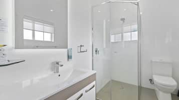 A modern bathroom with a glass-enclosed shower, a white sink, and a toilet.