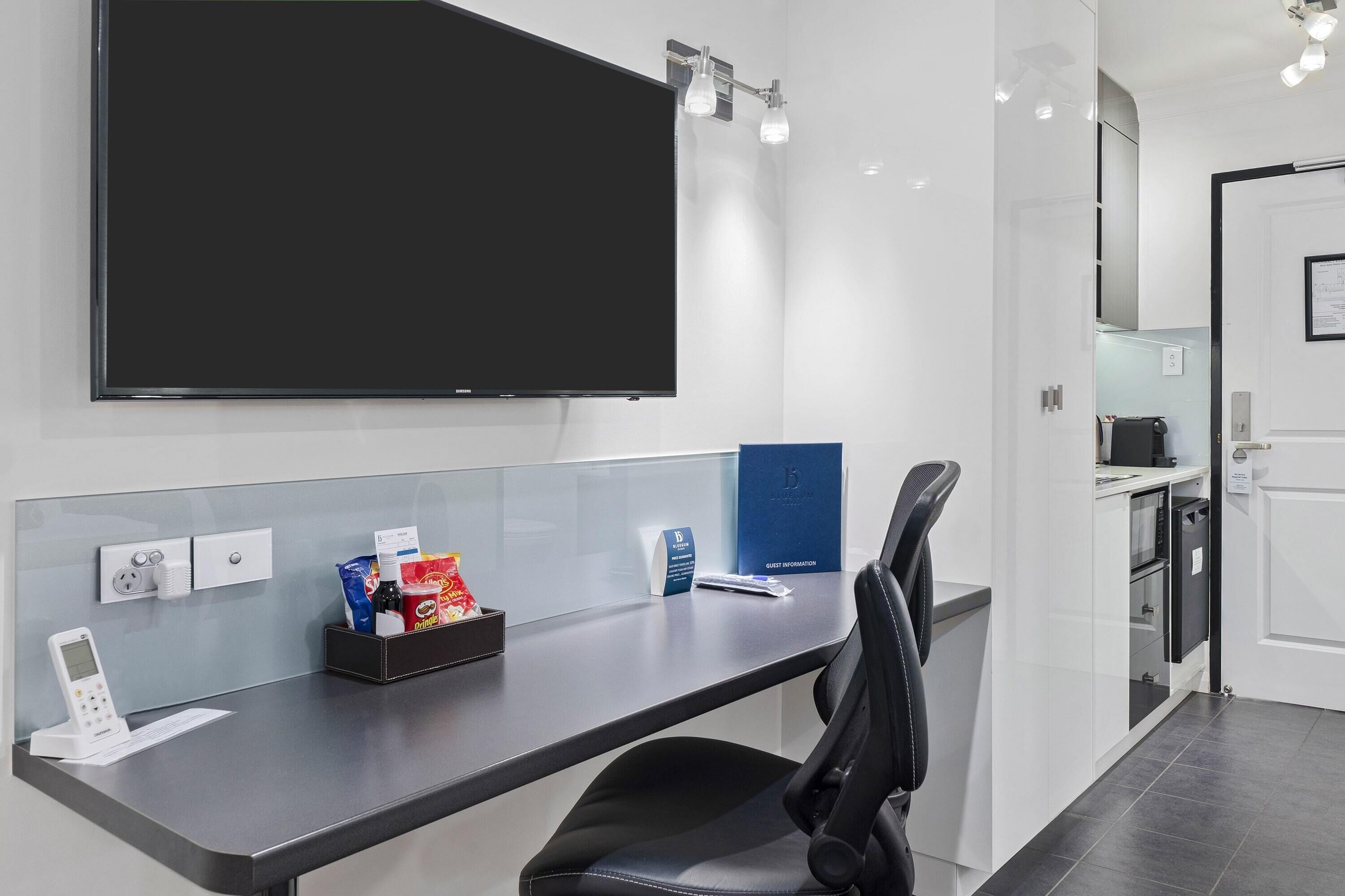 A modern hotel reception desk with a flat-screen TV, a digital keypad, and a guest information box.