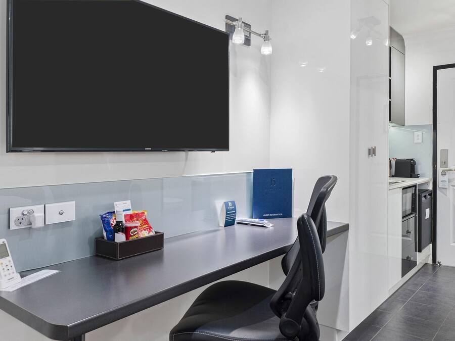 Un mostrador de recepción moderno de hotel, con un televisor de pantalla plana, un teclado digital y un expositor de información para huéspedes.